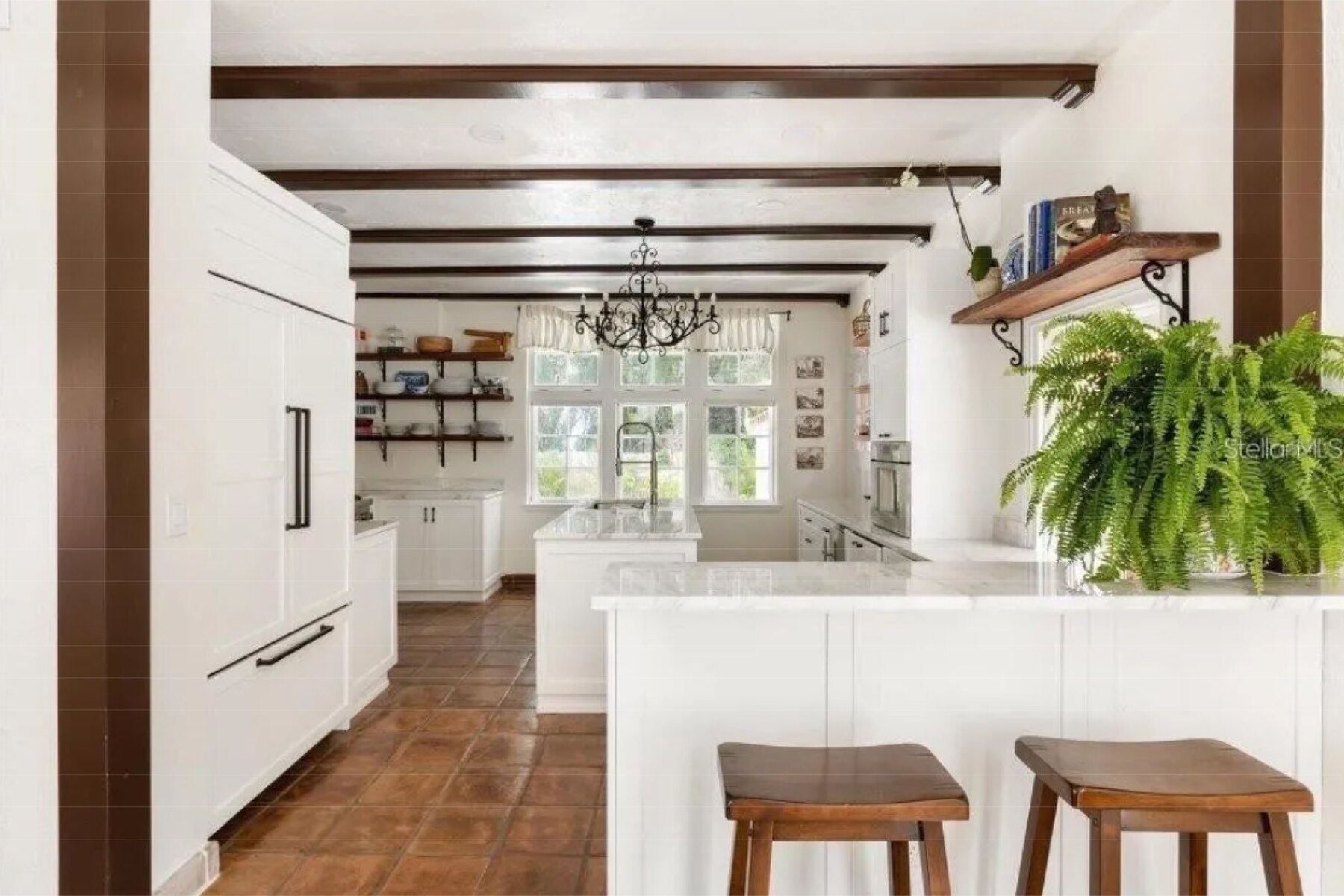 Kitchen breakfast bar with panel-ready refrigerator, wood stools and terracotta tile floor