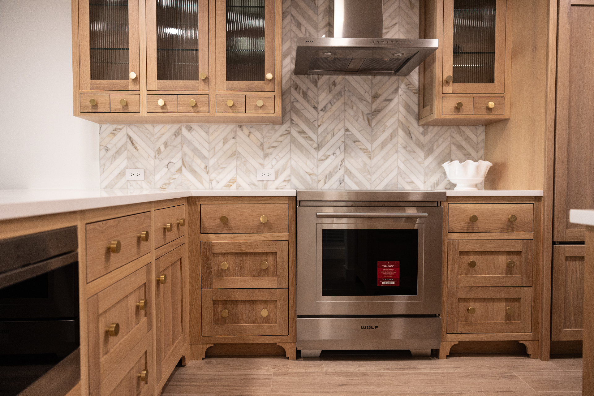 White oak kitchen with chevron marble backsplash and Wolf range