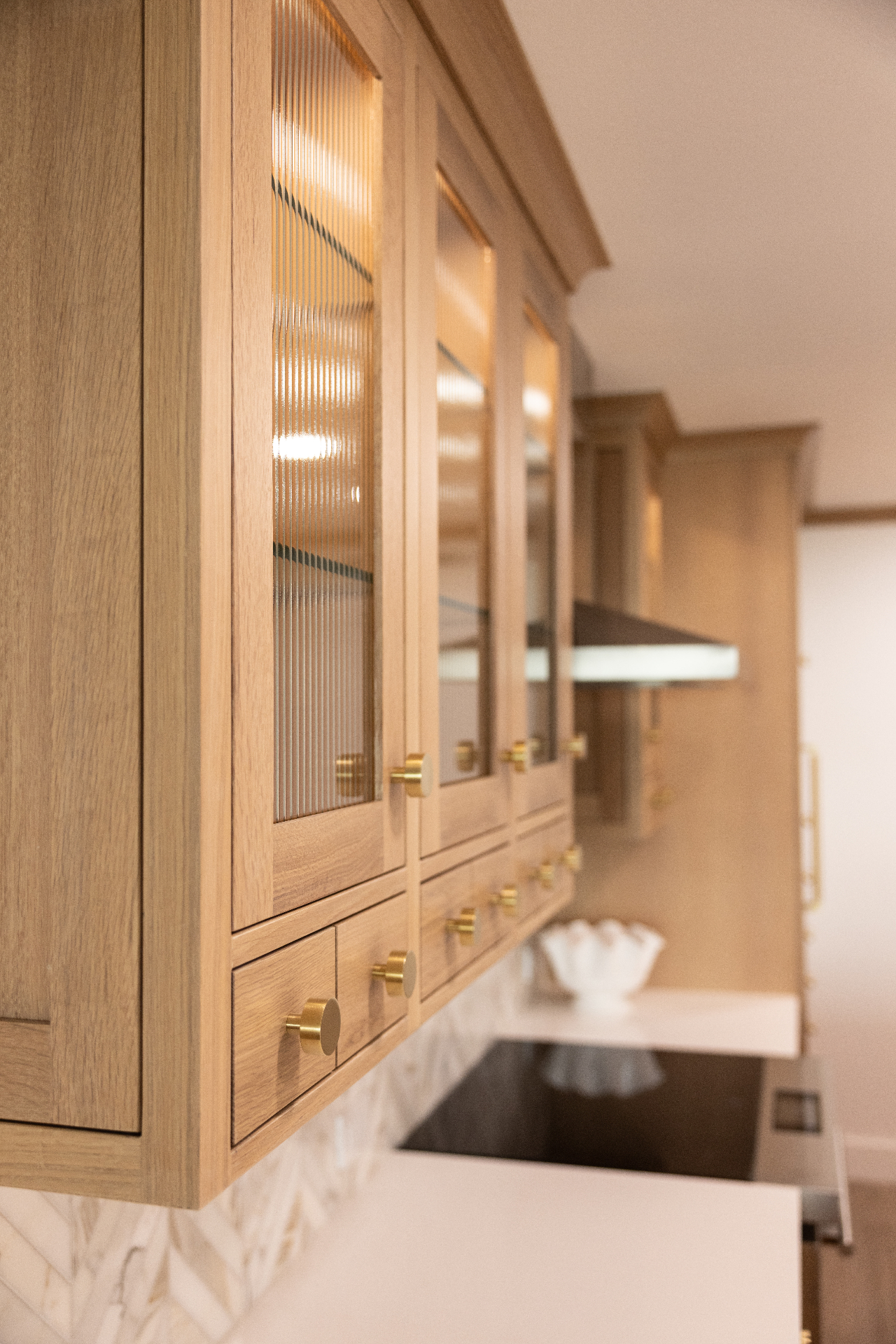 Close-up of white oak cabinets with reeded glass doors and brass pulls