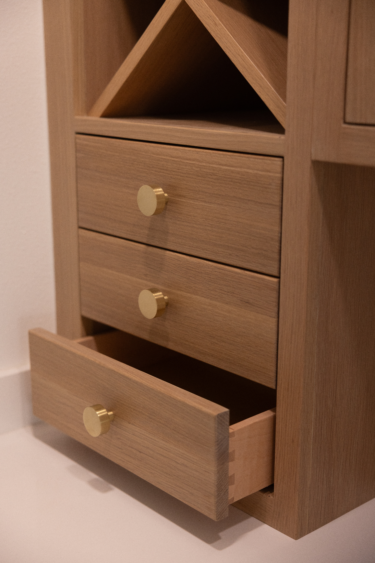 White oak drawer detail with brass knobs and open storage cubby