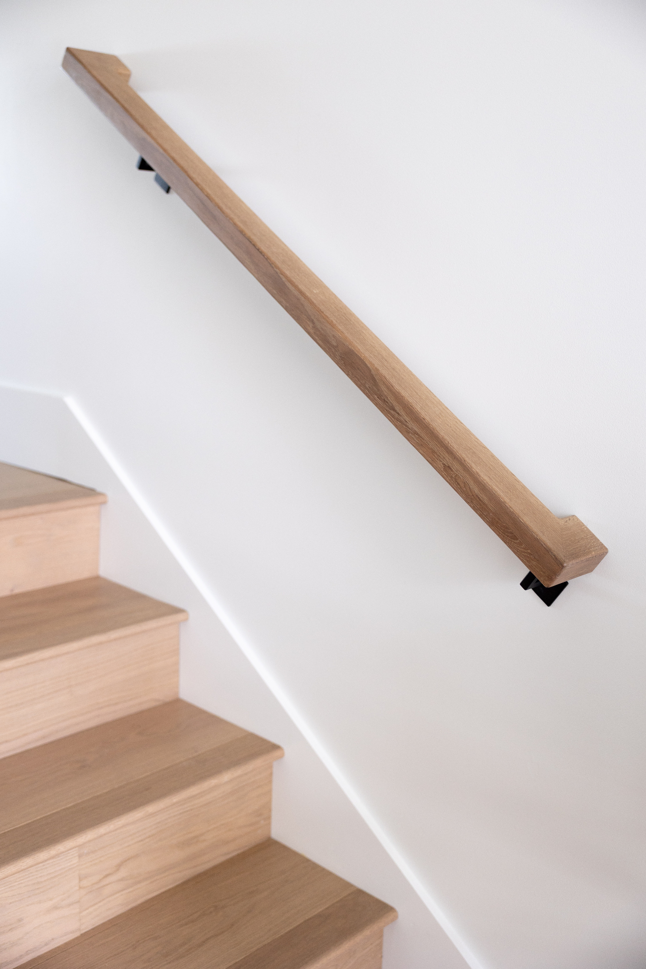 White oak wall-mounted handrail on staircase