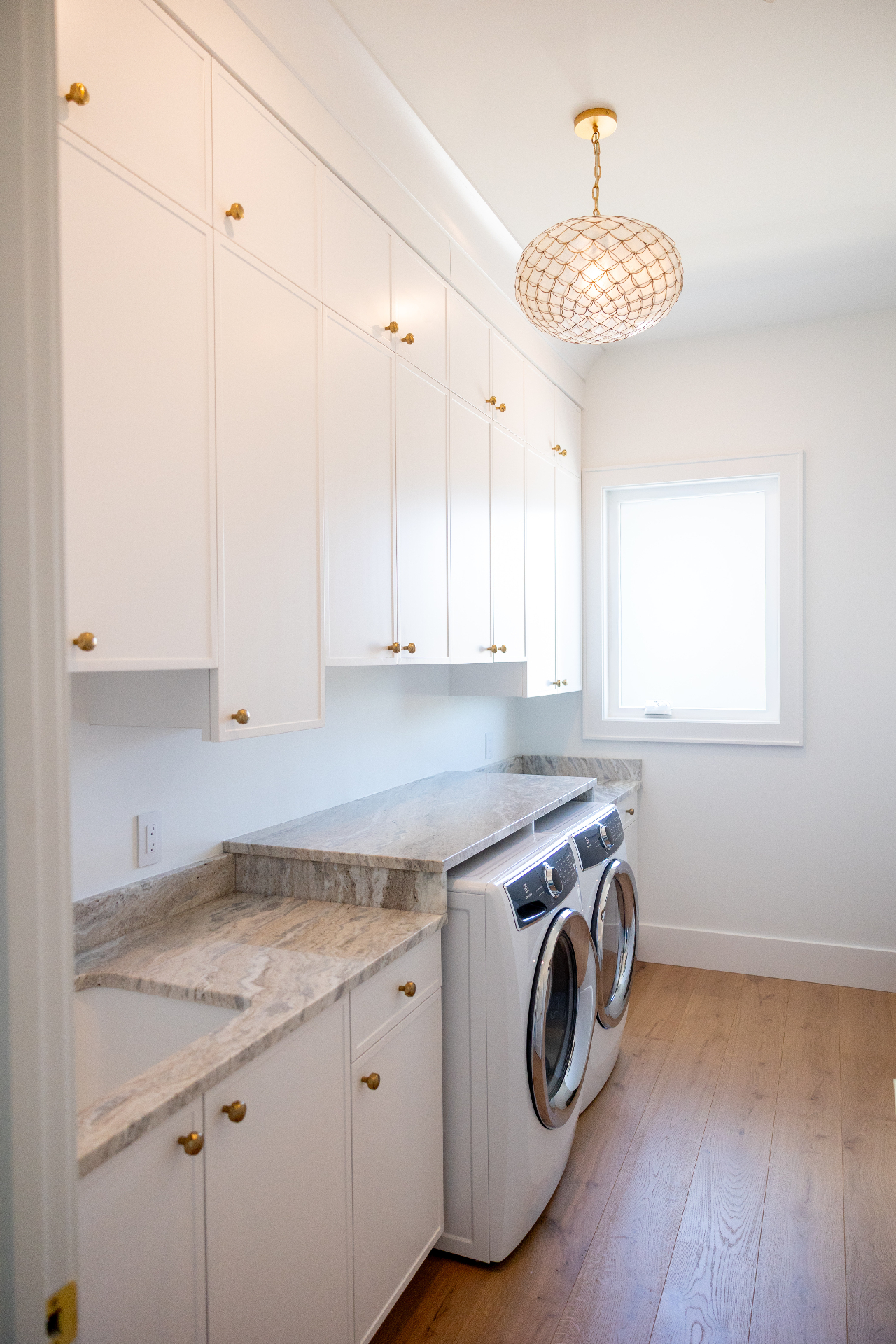White laundry room with stacked cabinetry and stone counters