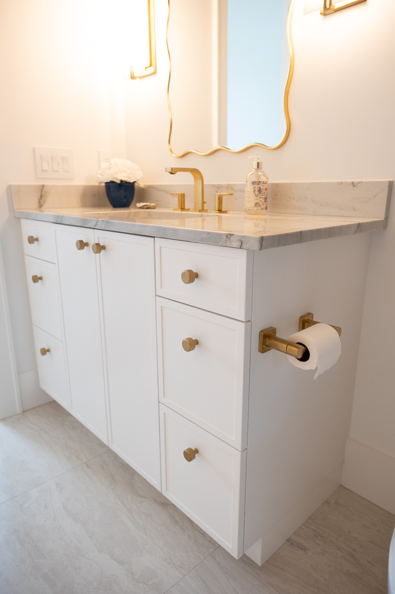 White vanity with marble top and brass fixtures