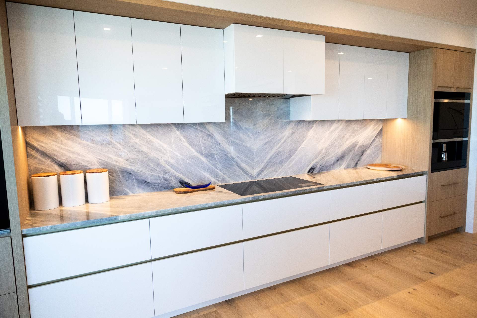 High-gloss white kitchen with marble backsplash