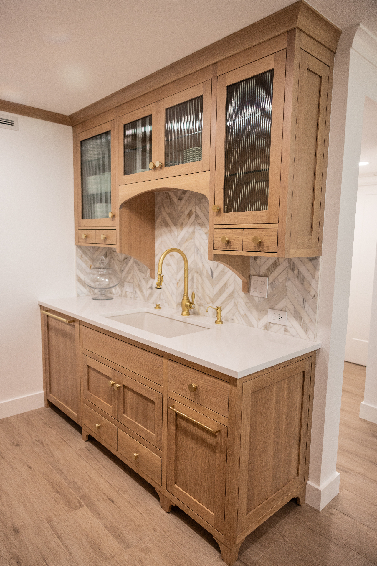 White oak bar cabinet with reeded glass and marble chevron backsplash